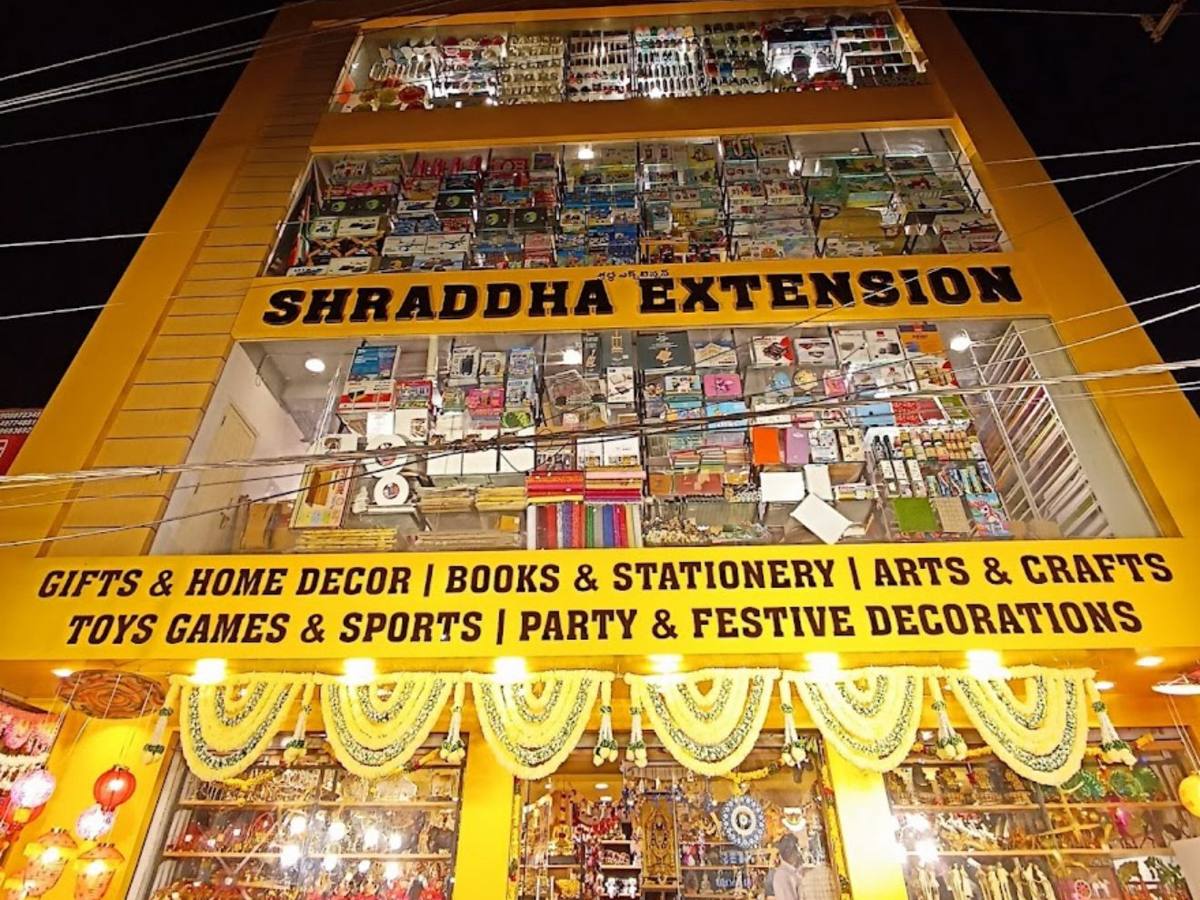 Shraddha Extension Kompally store front, a four-storey yellow building with lit display windows