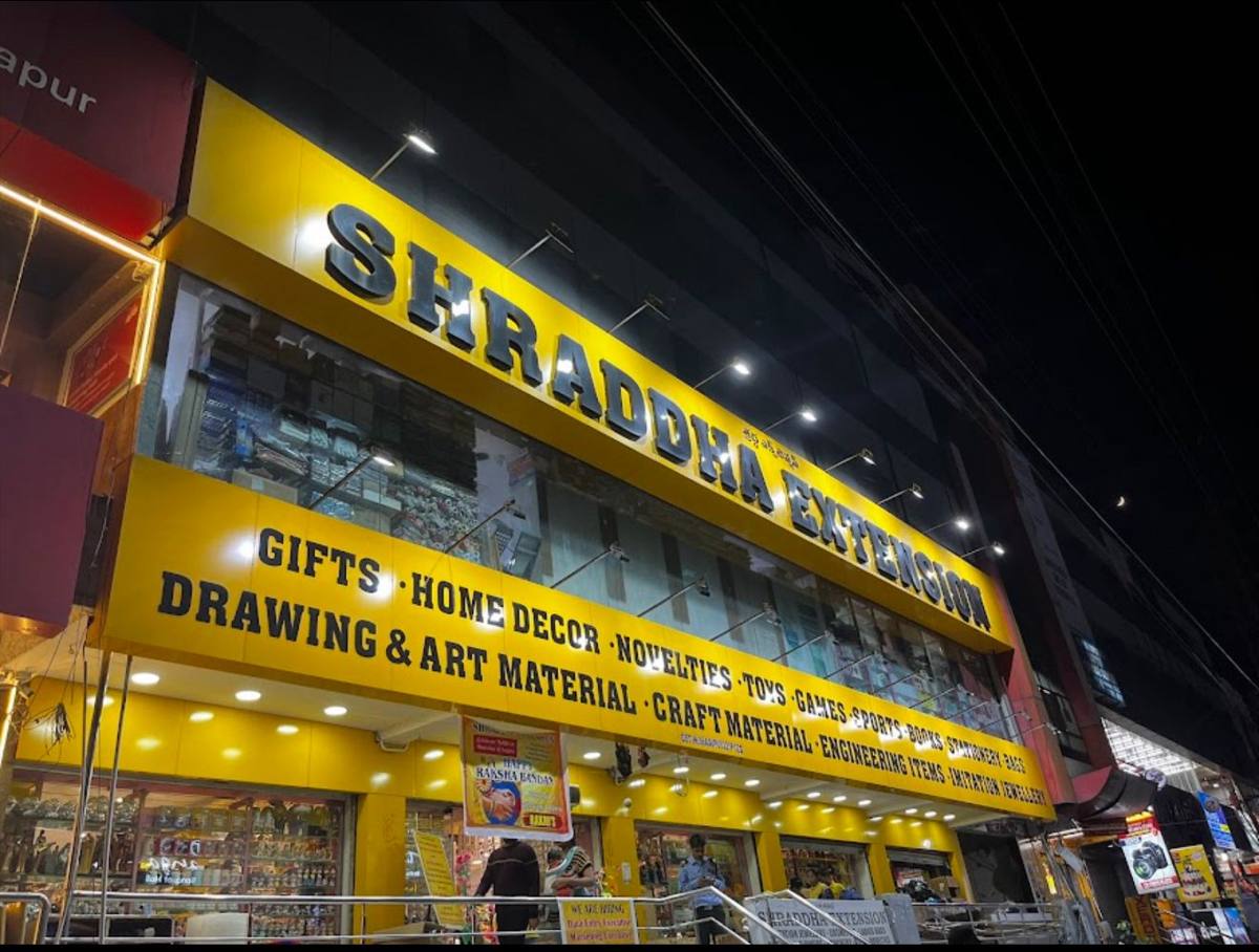 Shraddha Extension Miyapur store front at night, with its lit yellow signboard